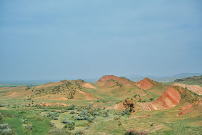 View of red mountains in spring, lush green fields under blue spring sky