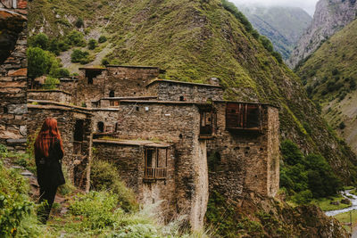 Rear view of woman looking at house by mountain