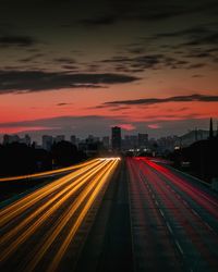 Light trails on road against sky at sunset