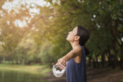 Woman enjoying fresh air with removed face mask in the forest during covid-19 pandemic.