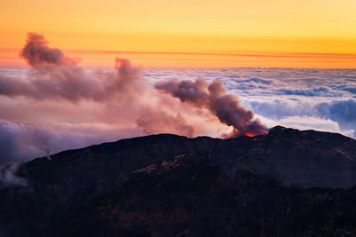 Smoke emitting from volcanic mountain during sunset