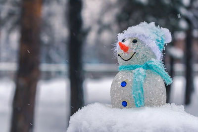 A toy snowman in a cold winter stands outdoors on the street