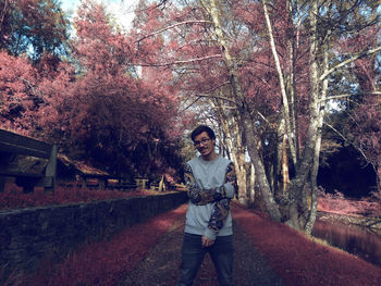 Portrait of smiling young man standing against trees