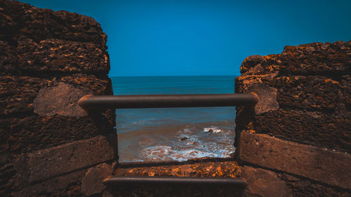 Scenic view of rocks by sea against blue sky