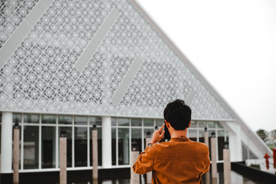 Rear view of man using mobile phone against sky