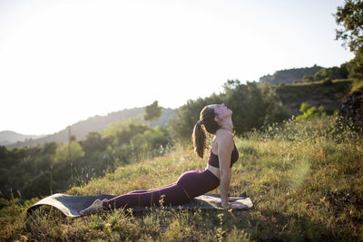 Side view of woman on grass against sky