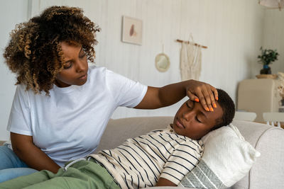 Loving worried african american woman mother taking care of sick child son at home
