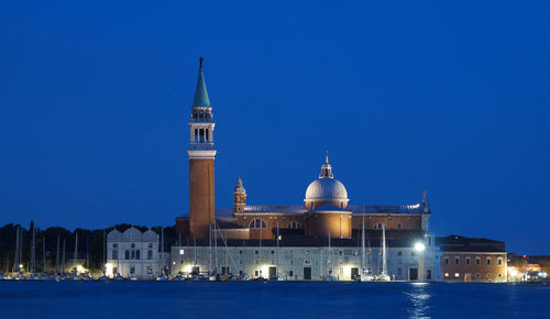 Illuminated cityscape against clear blue sky at night