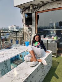 Portrait of woman sitting against building