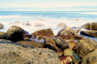 Panoramic shot of rocks on beach against sky