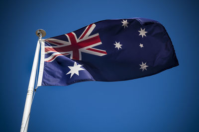 Low angle view of flag against blue sky