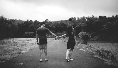 Rear view of couple walking on road against sky