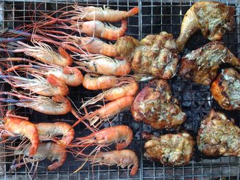 Directly above shot of tiger prawns with chicken meat on barbecue grill