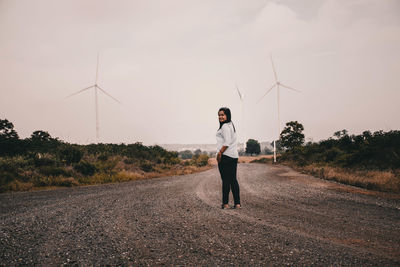 Portrait of woman standing on road against sky