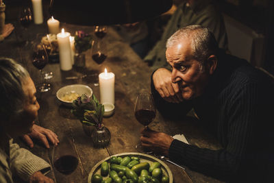 High angle view of mature man talking to senior female friend sitting at dining table during party