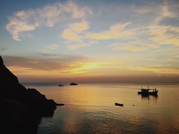 Silhouette boats in sea against sky during sunset