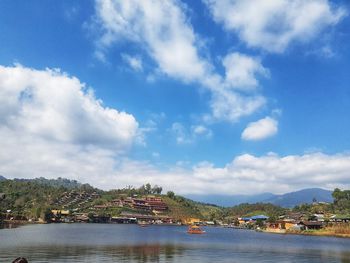 Scenic view of river by city against sky