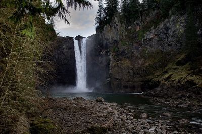 View of waterfall against cloudy sky
