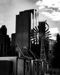 Low angle view of windmill against highrise buildings