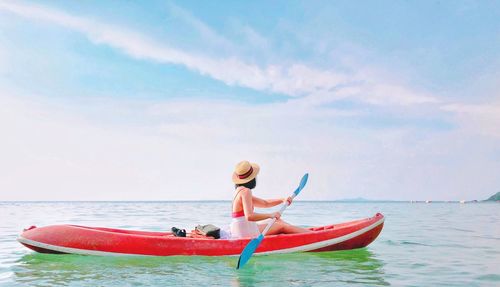 Woman kayaking in sea against sky