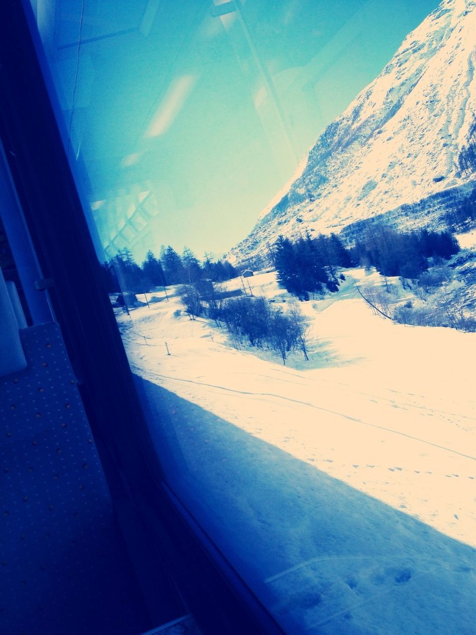 snow, transportation, winter, cold temperature, window, mountain, glass - material, transparent, season, sky, blue, vehicle interior, landscape, mode of transport, sunlight, nature, road, beauty in nature, day, travel