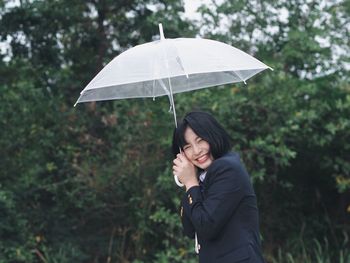 Portrait of smiling woman holding umbrella during rainy season