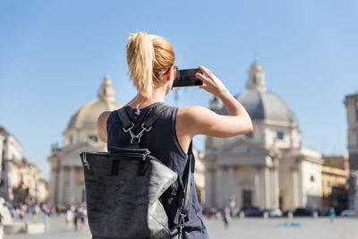 Rear view of woman photographing in city