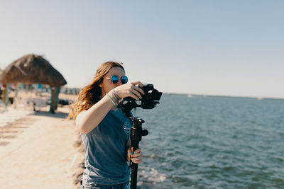 Man photographing at beach against clear sky