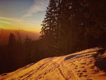 Scenic view of snow covered land against sky during sunset