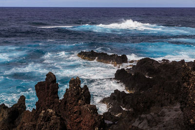 Scenic view of rocks in sea against sky