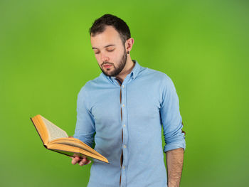 Young man holding book against gray background