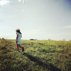 Girl walking on field against sky