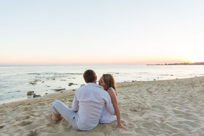 Rear view of couple sitting on beach