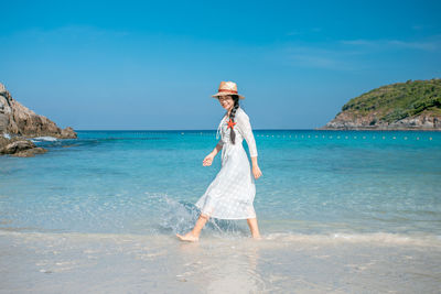 Full length of woman standing on beach against sky