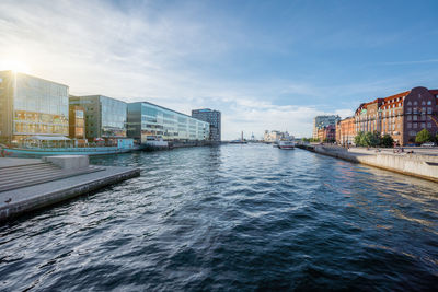 Buildings by river against sky in city