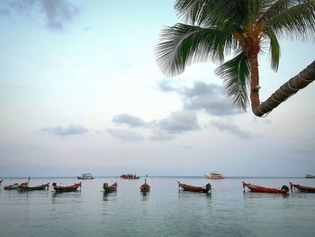 Boats in sea against cloudy sky