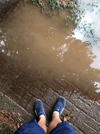 Low section of man standing by lake