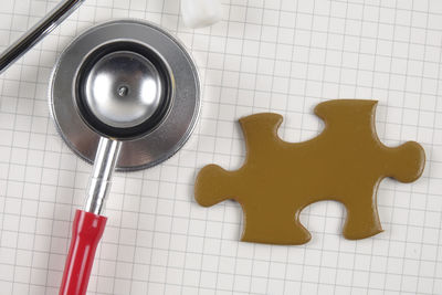 Directly above shot of stethoscope with jigsaw puzzle piece on notebook