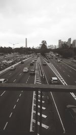 Vehicles on road against sky in city