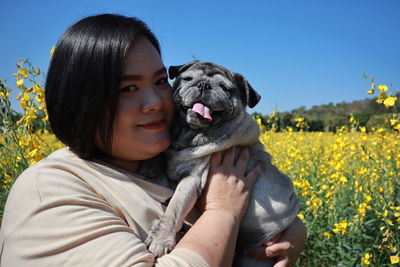 Portrait of smiling woman with dog standing in agricultural field