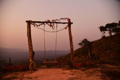 Metal structure on field against sky at sunset