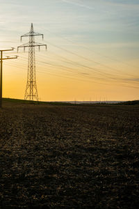 Electricity pylon on field against sky during sunset