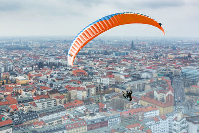 High angle view of woman paragliding over cityscape