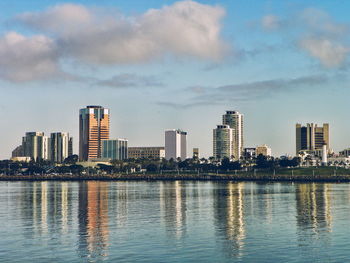 Scenic view of lake and cityscape against sky