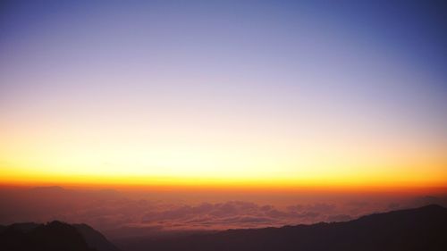 Scenic view of silhouette mountains against orange sky