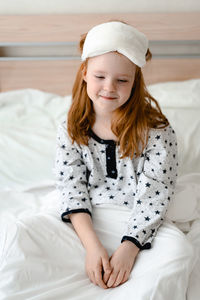 Portrait of young woman sitting on bed at home