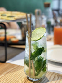 Mojito cocktail with lime and mint in glass on wooden table