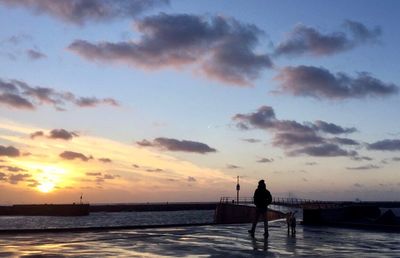 Silhouette man standing on beach against sky during sunset