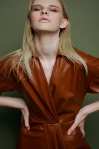 Portrait of young woman standing against wall