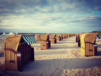 Hooded chairs on beach against sky